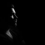 grayscale photo of man in black v neck shirt with black background